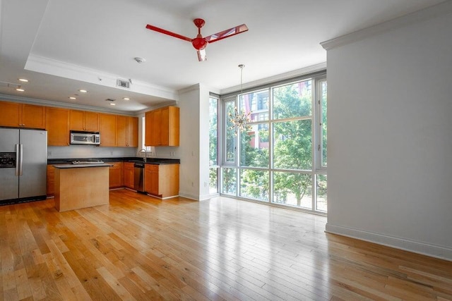 kitchen featuring ceiling fan, light wood-type flooring, ornamental molding, a kitchen island, and stainless steel appliances