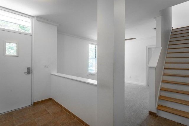 entrance foyer featuring dark colored carpet and crown molding