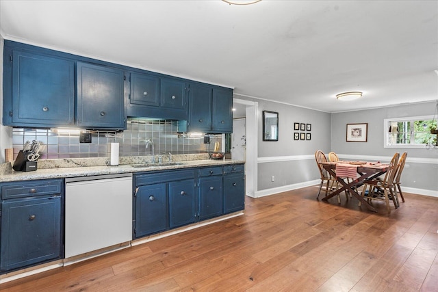 kitchen featuring white dishwasher, sink, blue cabinets, and backsplash