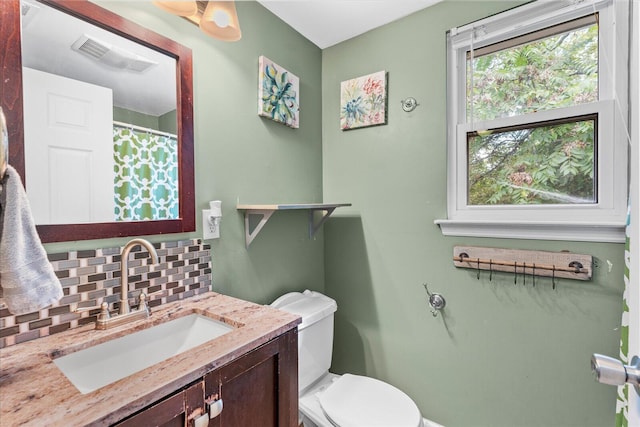 bathroom featuring vanity, backsplash, and toilet