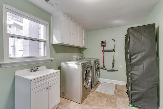 clothes washing area with cabinets, light tile patterned floors, washer and clothes dryer, and sink