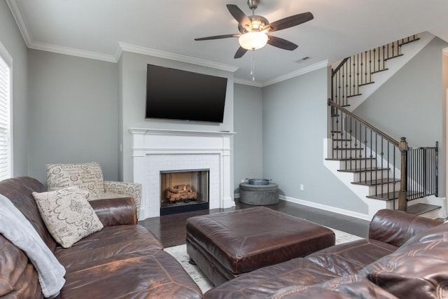 living room featuring hardwood / wood-style floors, ceiling fan, a fireplace, and crown molding