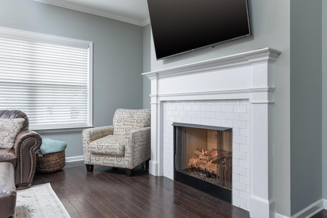 living area with dark hardwood / wood-style floors, crown molding, and a tiled fireplace