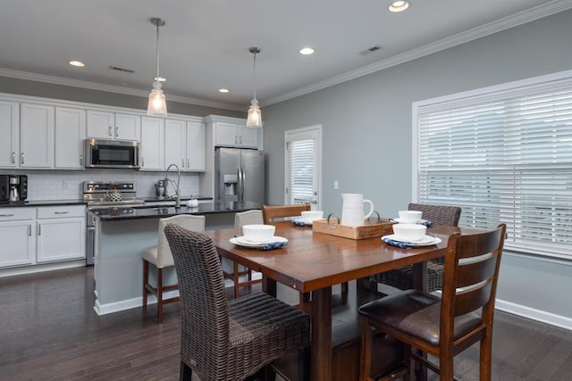 dining room featuring dark hardwood / wood-style flooring, ornamental molding, and sink