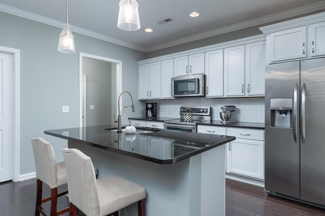 kitchen with backsplash, stainless steel appliances, sink, white cabinetry, and an island with sink