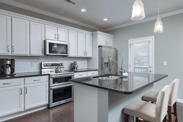 kitchen featuring tasteful backsplash, stainless steel appliances, sink, a center island with sink, and white cabinetry