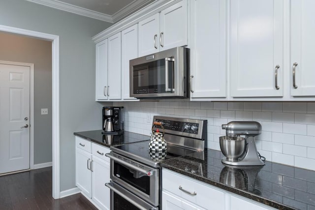 kitchen featuring stainless steel appliances, backsplash, dark stone countertops, crown molding, and white cabinets