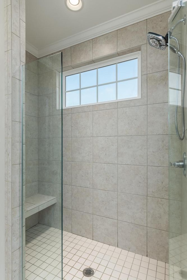 bathroom with tiled shower, a healthy amount of sunlight, and crown molding