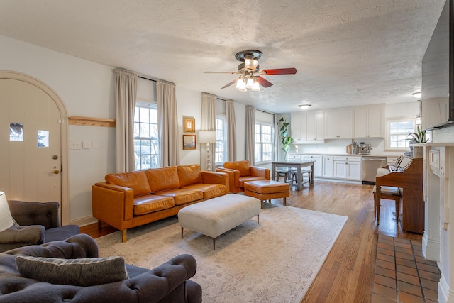 living room with ceiling fan, plenty of natural light, a textured ceiling, and light hardwood / wood-style flooring