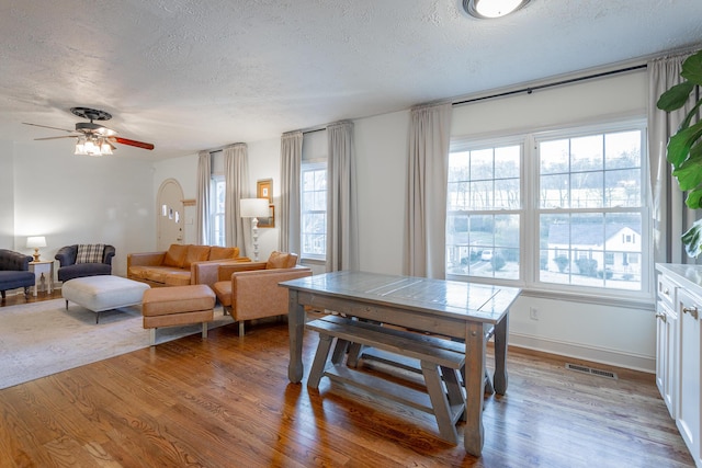 dining room with ceiling fan, a textured ceiling, and hardwood / wood-style flooring