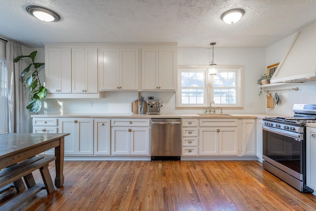 kitchen with pendant lighting, sink, white cabinetry, and stainless steel appliances