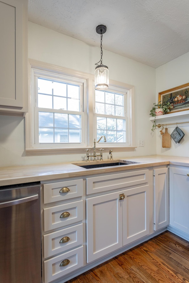 kitchen featuring dishwasher, sink, hanging light fixtures, dark hardwood / wood-style floors, and a textured ceiling