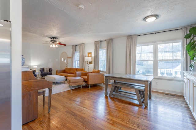 living room with ceiling fan, wood-type flooring, and a textured ceiling