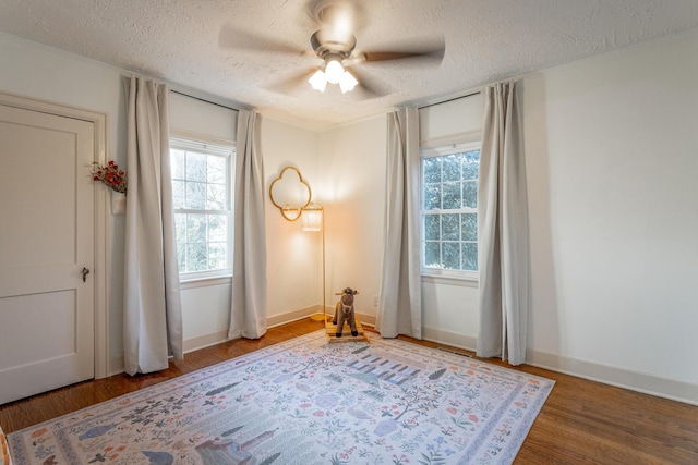 empty room with hardwood / wood-style floors, ceiling fan, and a textured ceiling