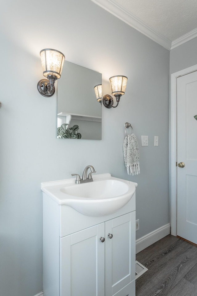 bathroom featuring hardwood / wood-style flooring, vanity, a textured ceiling, and ornamental molding