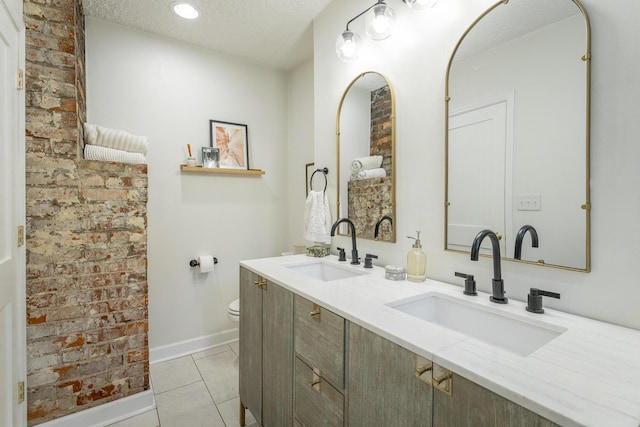 bathroom with tile patterned flooring, vanity, toilet, and a textured ceiling