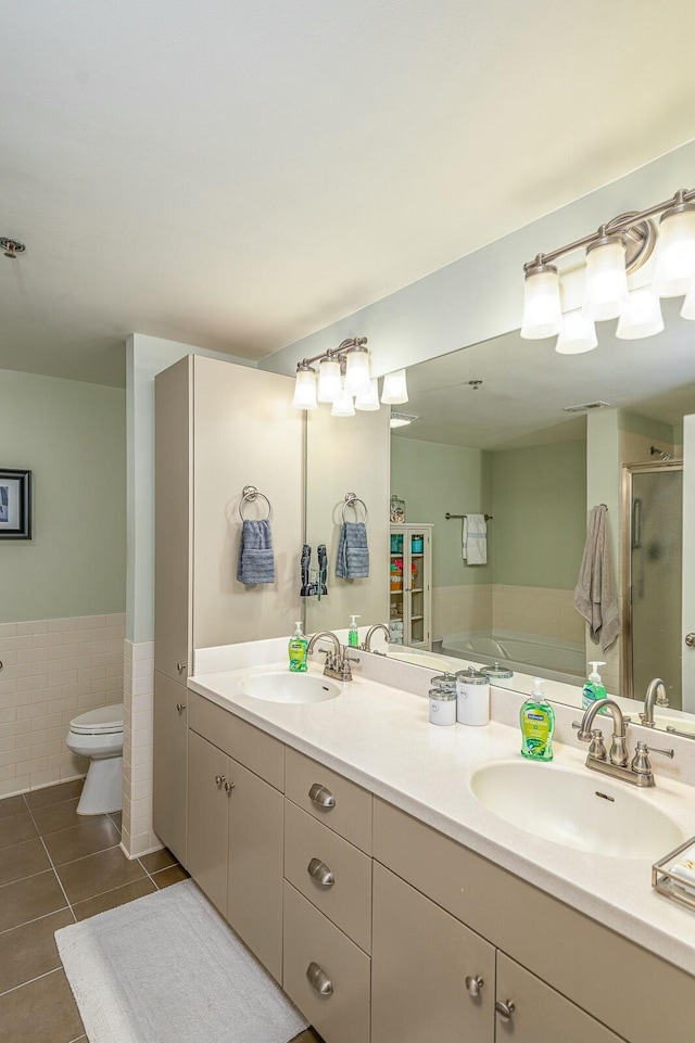 full bathroom with tile patterned flooring, toilet, plus walk in shower, vanity, and tile walls