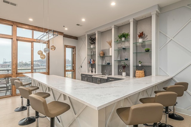 kitchen with a kitchen bar, built in shelves, hanging light fixtures, and kitchen peninsula