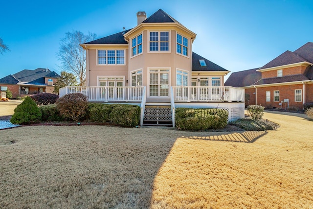 rear view of house featuring a lawn and a wooden deck