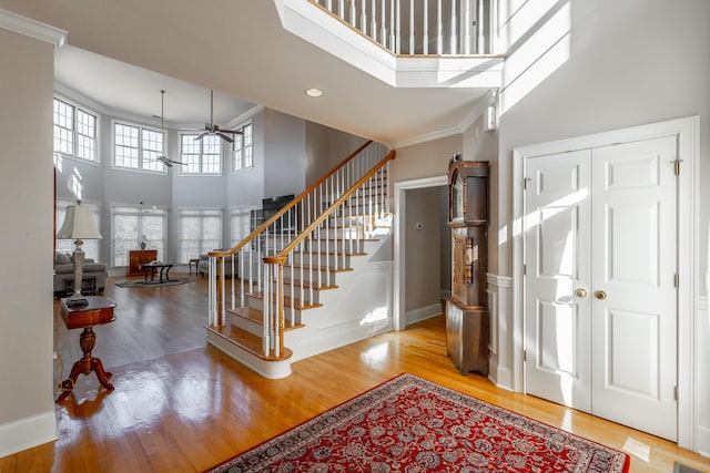 entrance foyer featuring a high ceiling, ceiling fan, crown molding, and hardwood / wood-style floors