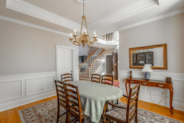 dining area featuring a raised ceiling, crown molding, light hardwood / wood-style flooring, and an inviting chandelier