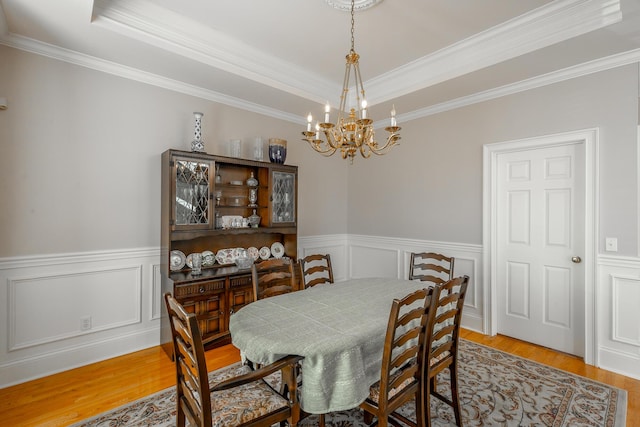 dining area featuring a chandelier, hardwood / wood-style flooring, a tray ceiling, and crown molding