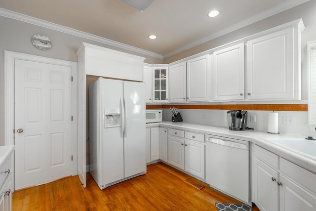 kitchen featuring white appliances, white cabinets, sink, crown molding, and light wood-type flooring