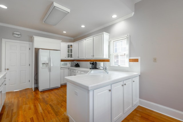 kitchen with kitchen peninsula, sink, white cabinets, and white appliances