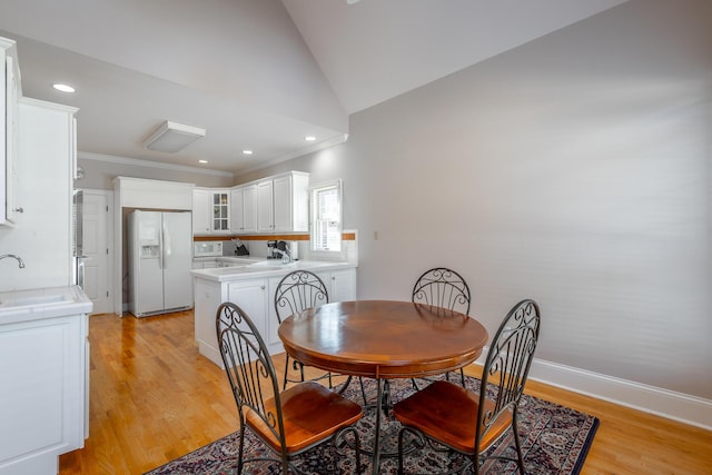 dining room with crown molding, sink, vaulted ceiling, and light hardwood / wood-style flooring