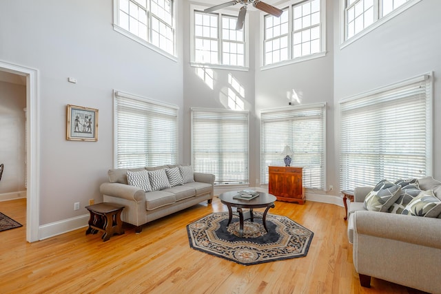 living room with a high ceiling, hardwood / wood-style flooring, and ceiling fan