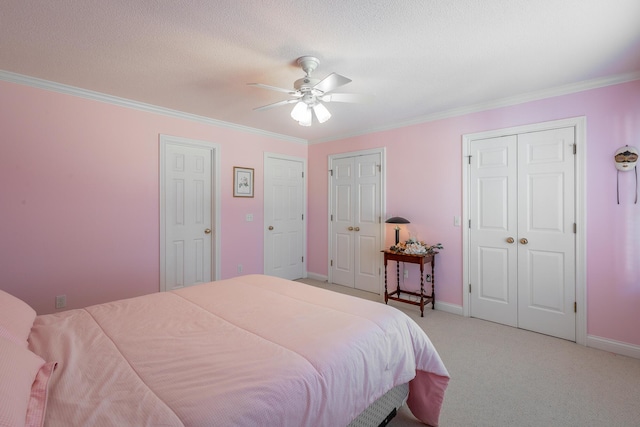 carpeted bedroom with ceiling fan, crown molding, and two closets