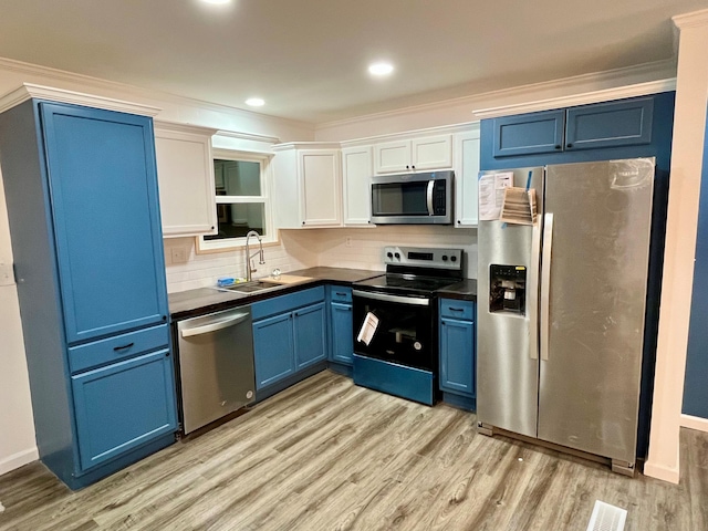 kitchen with blue cabinets, sink, tasteful backsplash, stainless steel appliances, and light hardwood / wood-style floors