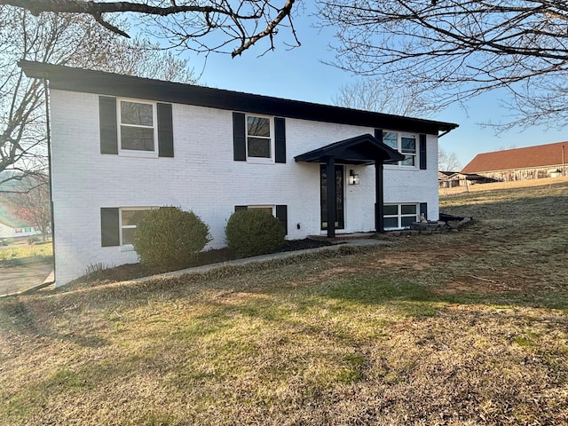 raised ranch with brick siding and a front yard