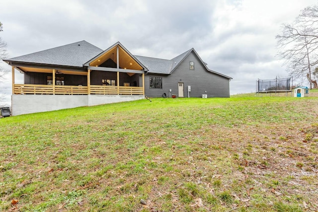 rear view of property featuring a lawn and a trampoline