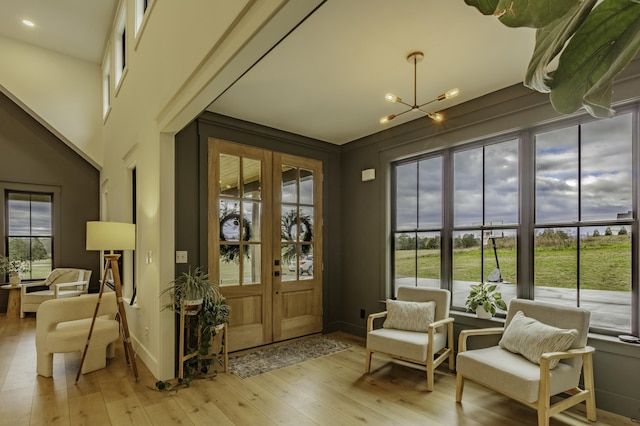 sitting room featuring french doors, light wood-type flooring, an inviting chandelier, and plenty of natural light