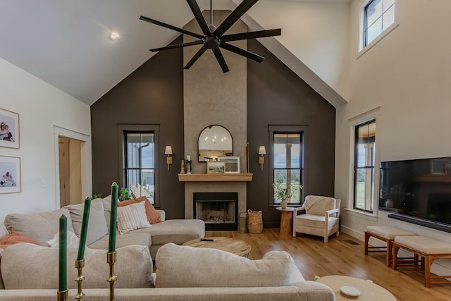 living room featuring a fireplace, ceiling fan, light hardwood / wood-style flooring, and high vaulted ceiling