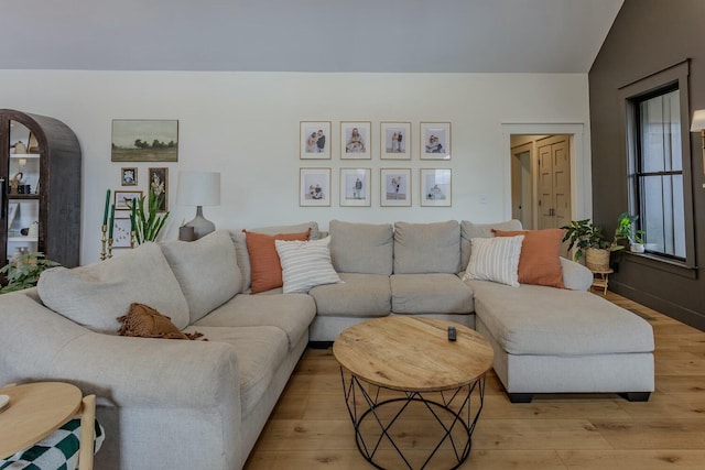 living room with light hardwood / wood-style floors and vaulted ceiling