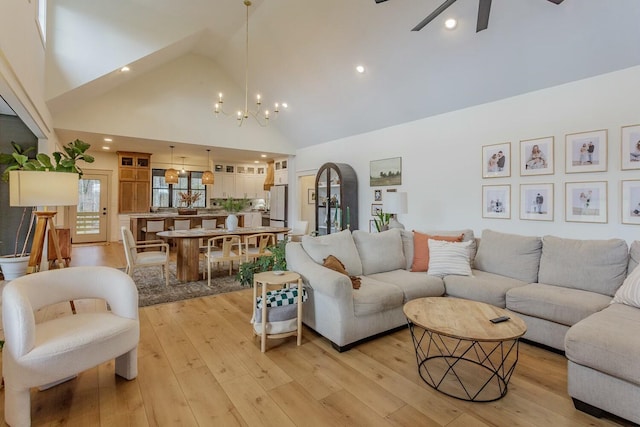 living room featuring ceiling fan with notable chandelier, high vaulted ceiling, and light hardwood / wood-style flooring