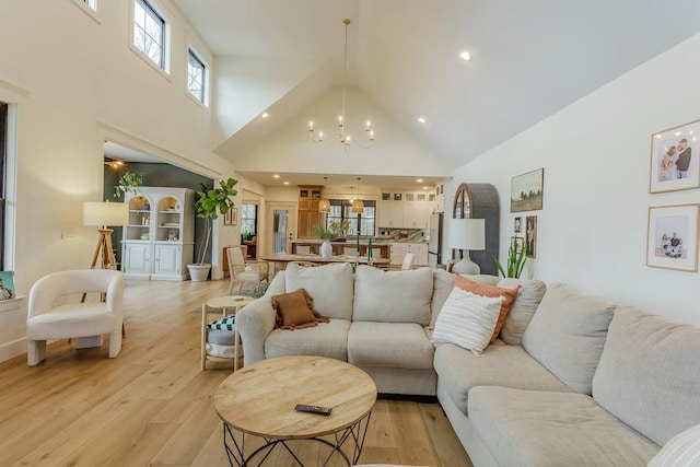 living room with light hardwood / wood-style floors, a high ceiling, and an inviting chandelier