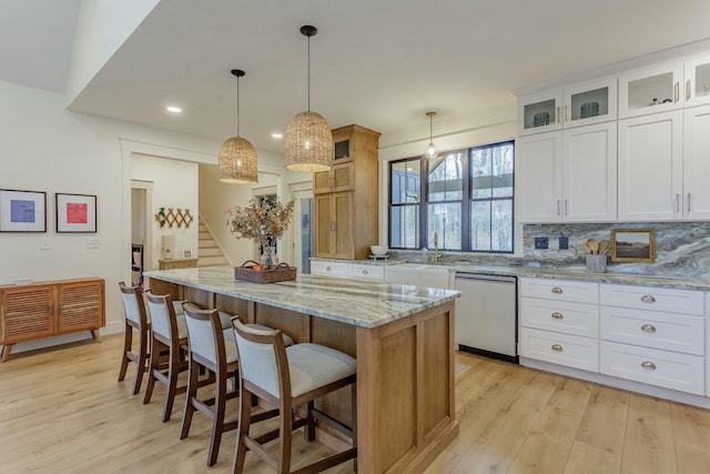 kitchen with dishwashing machine, a kitchen island, light wood-type flooring, and white cabinetry