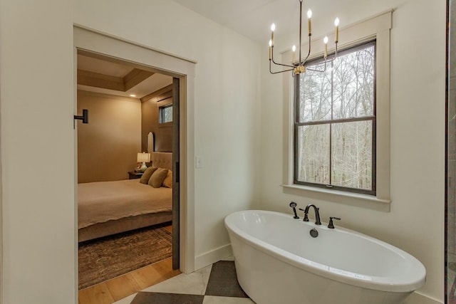 bathroom featuring wood-type flooring, a bath, a tray ceiling, and a chandelier