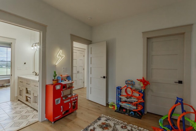 recreation room featuring light wood-type flooring and sink