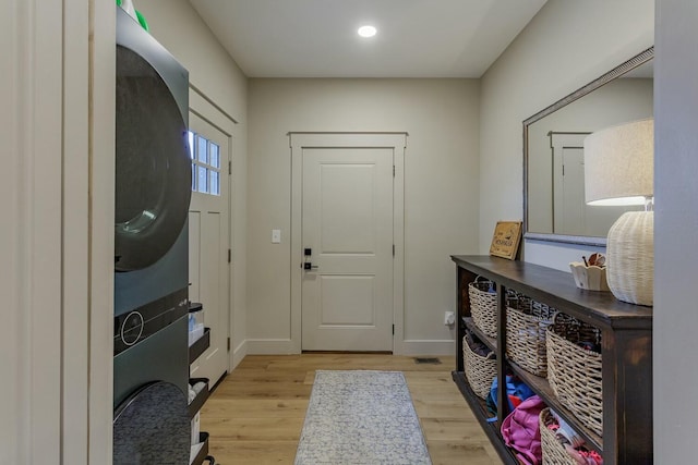 entrance foyer with stacked washer and dryer and light hardwood / wood-style flooring