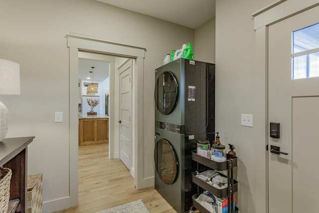 washroom with light hardwood / wood-style floors and stacked washer and clothes dryer