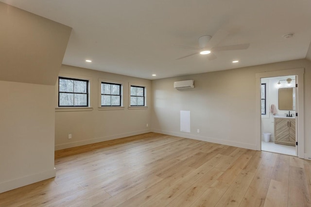 spare room with light hardwood / wood-style floors, a wall mounted AC, and ceiling fan