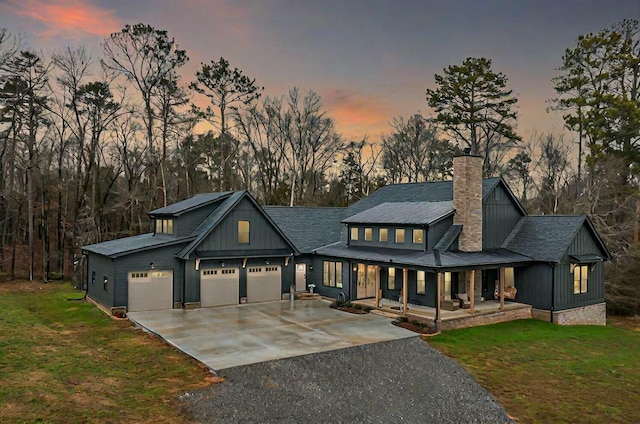 view of front of house featuring covered porch, a garage, and a lawn