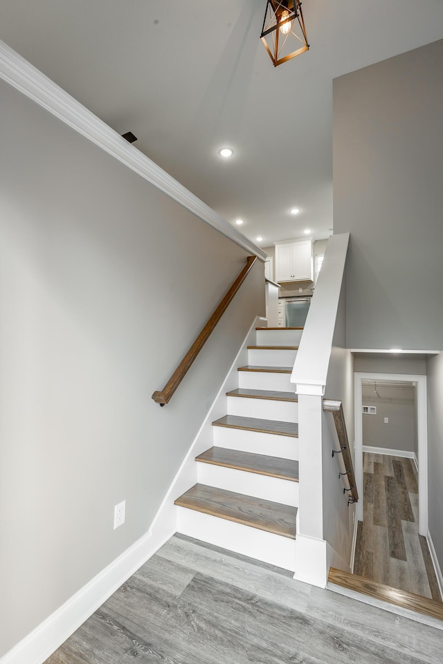 stairs with hardwood / wood-style flooring and crown molding