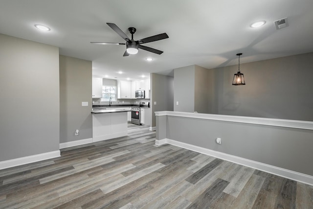 unfurnished living room with sink, ceiling fan, and light hardwood / wood-style flooring