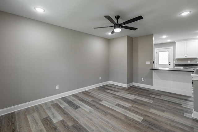 unfurnished living room featuring ceiling fan and dark wood-type flooring