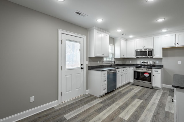 kitchen featuring appliances with stainless steel finishes, white cabinetry, sink, and wood-type flooring